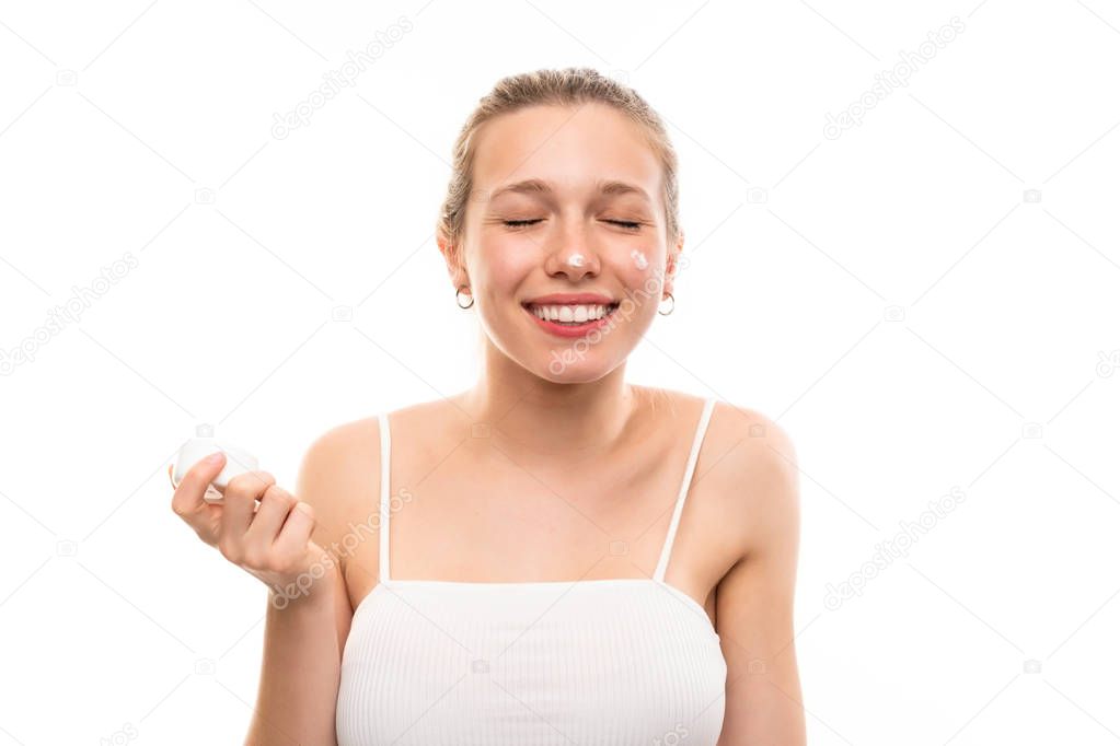 Young blonde woman over isolated white background with moisturizer