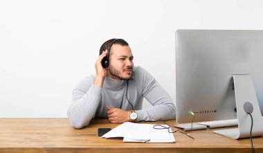 Telemarketer Kolombiyalı adam kulağına el koyarak bir şey dinliyor
