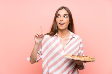 İzole pembe duvar üzerinde pizza tutan genç kadın parmağını kaldırırken çözümü gerçekleştirmek niyetinde