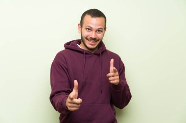 Yeşil duvar üzerinde sweatshirt ile Kolombiyalı adam size parmak