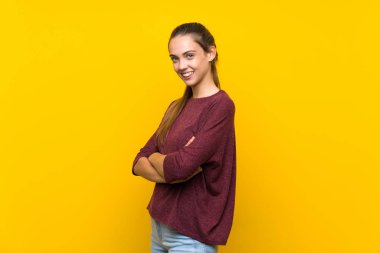 Kolları çapraz izole sarı arka plan üzerinde genç kadın geçti ve ileriye bakıyor