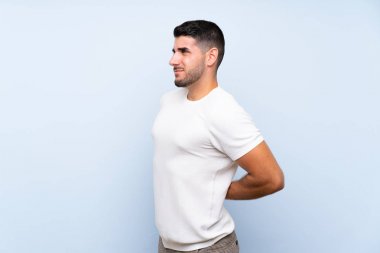 Kafkas yakışıklı adam izole mavi arka plan üzerinde bir çaba yapmış olduğu için sırt ağrısı muzdarip