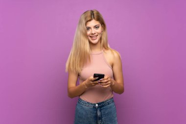 Cep telefonu ile bir mesaj göndererek izole mor arka plan üzerinde Genç kız