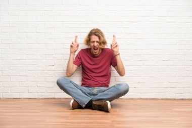 Sarışın adam parmakları geçerken yerde oturan