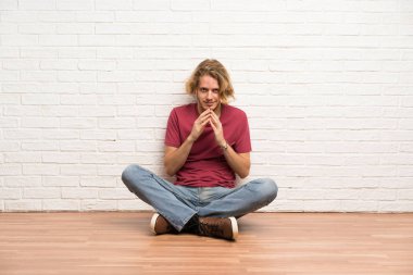 Sarışın adam yerde oturmuş bir şeyler entrika