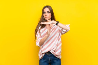 Izole sarı arka plan üzerinde genç kadın jest zaman dışarı yapma