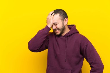 Sarı duvar üzerinde sweatshirt ile Kolombiyalı adam bir şey fark etti ve çözüm niyetinde