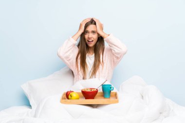 Sürpriz yüz ifadesi ile kahvaltı ile sabahlık genç kadın