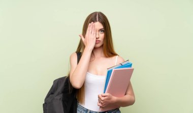 Elle bir göz kapsayan izole yeşil arka plan üzerinde genç öğrenci kadın