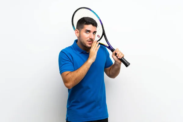 孤立した白い壁の上にハンサムな若いテニスプレーヤーの男が何かをささやく — ストック写真