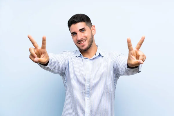 Kavkazský Pohledný Muž Přes Izolované Modré Pozadí Usmívá Zobrazuje Vítězné — Stock fotografie