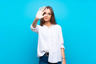 İzole edilmiş mavi arka plan üzerinde genç bir kadın parmaklarıyla beşi sayıyor