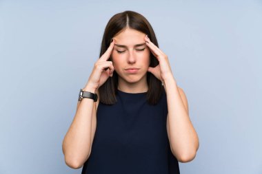 Izole mavi duvar üzerinde genç kadın mutsuz ve bir şey ile sinirli. Negatif yüz ifadesi