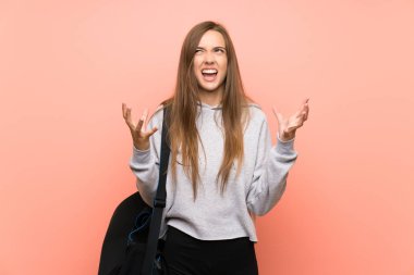 Izole pembe arka plan üzerinde Genç spor kadın mutsuz ve bir şey ile sinirli