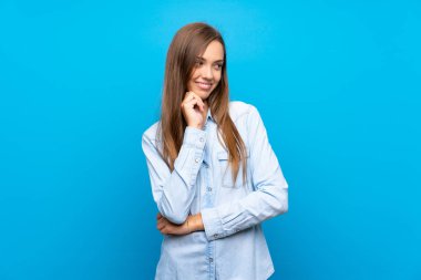 Soyutlanmış mavi arka planda genç bir kadın yan tarafa bakıyor.
