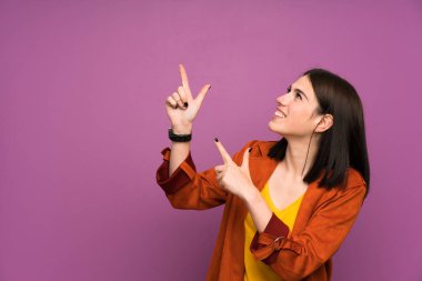 İşaret parmağı ile işaret izole mor arka plan üzerinde bir ceket ile genç kadın harika bir fikir
