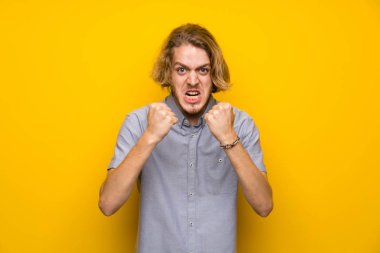 Izole sarı arka plan üzerinde Blonde adam kötü bir durum tarafından sinirli