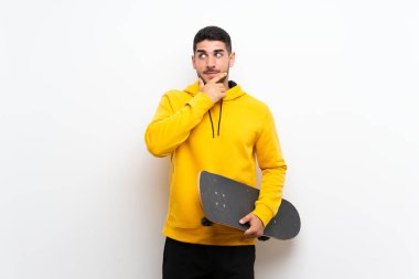 Izole beyaz duvar üzerinde yakışıklı genç patenci adam bir fikir düşünme