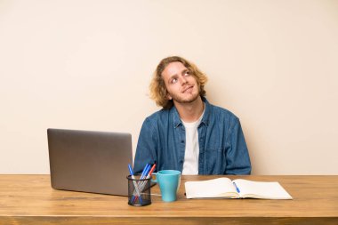 Bir dizüstü bilgisayar gülerek ve yukarı bakıyor sarışın adam