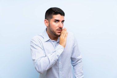 Izole mavi arka plan üzerinde kafkas yakışıklı adam bir şey fısıldıyor