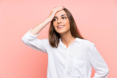 Genç bir kadın pembe arka planda gülüyor.