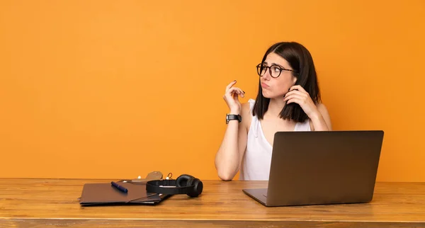 Business woman in a office making doubts gesture looking side