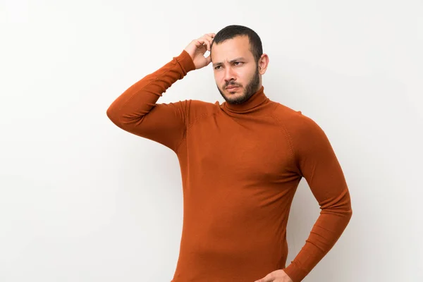 Colombian man with turtleneck sweater having doubts while scratching head