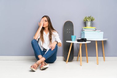 Yerde oturan genç kadın bir gözü elle kaplayarak