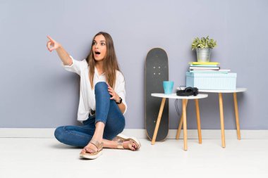 Genç bir kadın yerde oturmuş işaret ediyor.