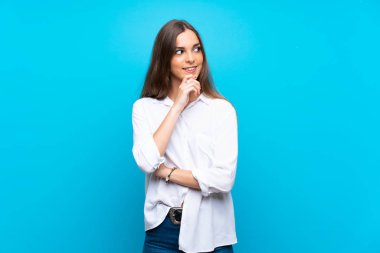 Soyutlanmış mavi arka planda genç bir kadın yan tarafa bakıyor.