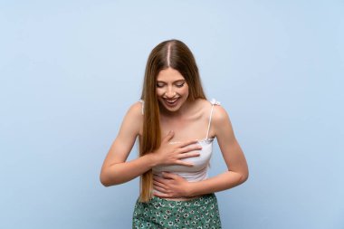 Soyutlanmış mavi arka planda genç bir kadın. Çok gülümsüyor.