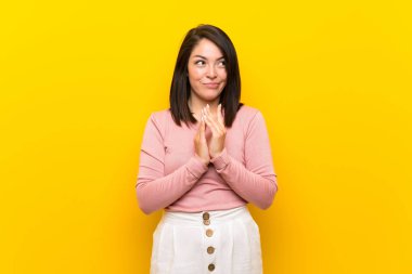 Izole sarı arka plan üzerinde genç Meksikalı kadın bir şey entrika