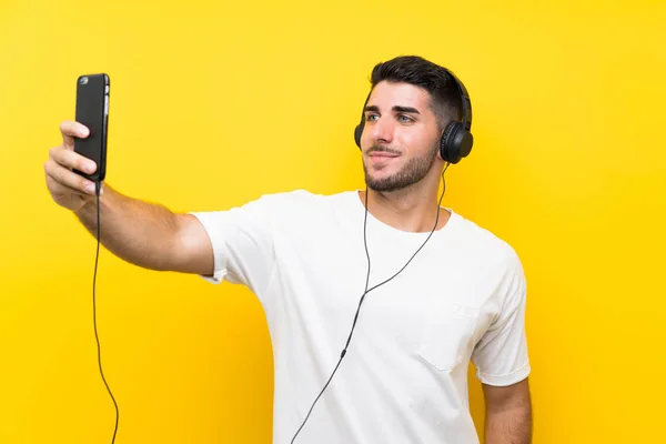 Junger Gutaussehender Mann Hört Musik Mit Handy Über Isolierter Gelber — Stockfoto