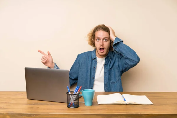 Homem Loiro Com Laptop Surpreso Apontando Dedo Para Lado — Fotografia de Stock