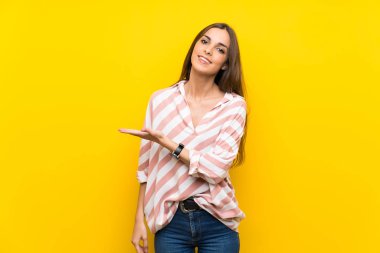 İzole edilmiş sarı arka planda genç bir kadın gülümserken bir fikir sunuyor.