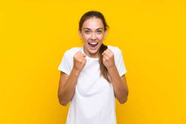 Sarı arka planda zafer kutlaması yapan genç bir kadın.