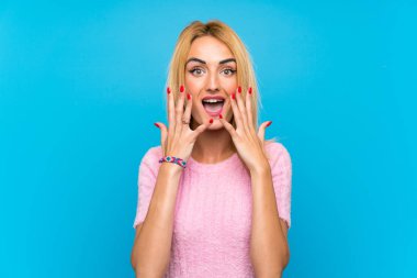 Sürpriz yüz ifadesi ile mavi arka plan üzerinde genç sarışın kadın