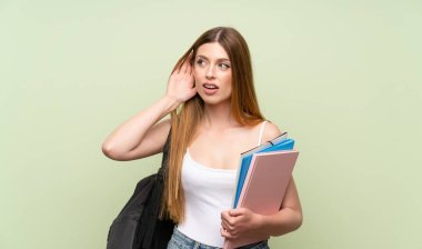 Izole yeşil arka plan üzerinde genç öğrenci kadın bir şey dinlerken