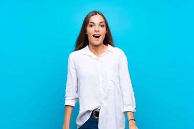 Soyutlanmış mavi arka planı olan genç bir kadın. Şaşırtıcı bir yüz ifadesi.