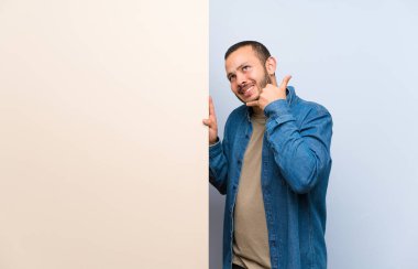 Kolombiyalı adam telefon jesti yaparak boş bir pankart tutan