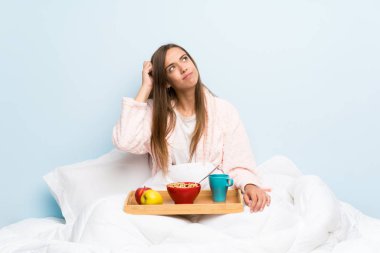 Kahvaltı ile sabahlık genç kadın şüpheleri olan ve yüz ifadesi karıştırarak