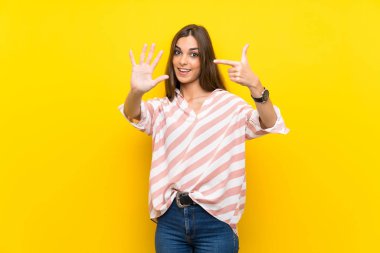 Izole sarı arka plan üzerinde genç kadın parmakları ile yedi sayma