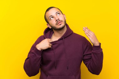 Yorgun ve hasta ifade ile sarı duvar üzerinde Sweatshirt ile Kolombiyalı adam