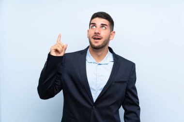 Soyutlanmış mavi arka planda yakışıklı bir adam yukarı bakıyor ve şaşırıyor.