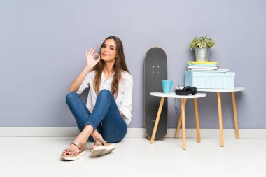 Yerde oturan genç kadın parmaklarıyla 