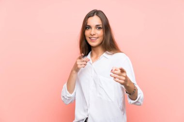 Izole pembe arka plan üzerinde genç kadın size parmak