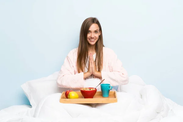 Young woman in dressing gown with breakfast pleading