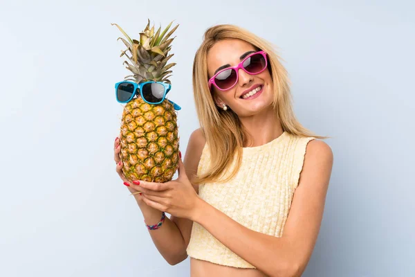 Güneş gözlüğü ile bir ananas tutan genç sarışın kadın — Stok fotoğraf