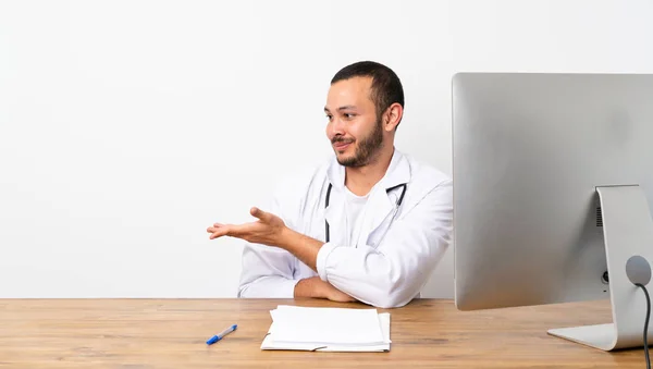 Doctor Colombian man presenting an idea while looking smiling towards