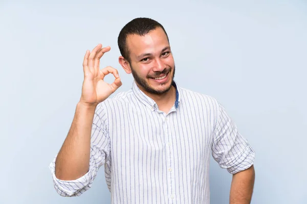 Kolumbijski Człowiek Białym Tle Niebieską Ścianę Pokazując Znak Palcami — Zdjęcie stockowe